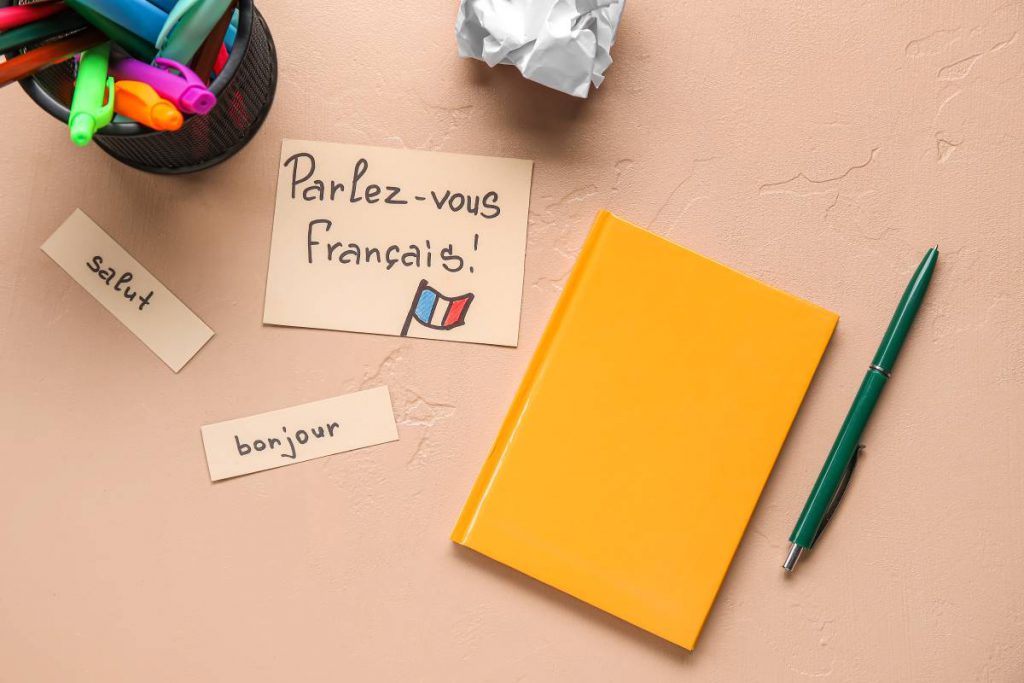 Des mots français sur un cahier et des stylos. Outils pour l'évaluation de la maîtrise du français pour obtenir la citoyenneté française en tant que Tunisien.