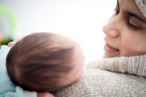 Une mère regarde tendrement son nouveau-né, symbolisant le congé de naissance en Tunisie.