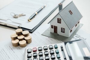 Calculatrice, maison miniature et pièces de monnaie représentant le prêt CNRPS pour l'immobilier